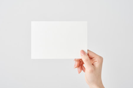 Woman's hand holding white paper and white backgroundの写真素材