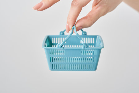 Hand of a woman holding a small shopping basketの写真素材
