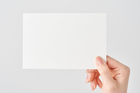 Woman's hand holding white paper and white backgroundの写真素材