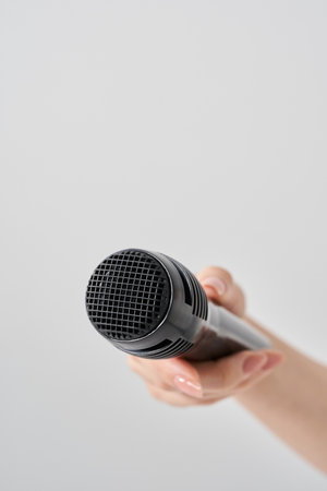 Woman's hand holding a wireless microphone and white backgroundの写真素材