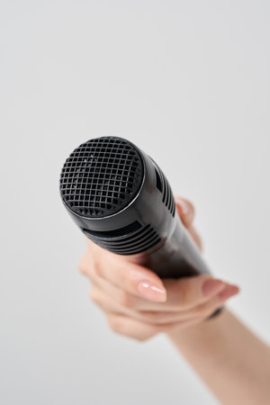 Woman's hand holding a wireless microphone and white backgroundの写真素材