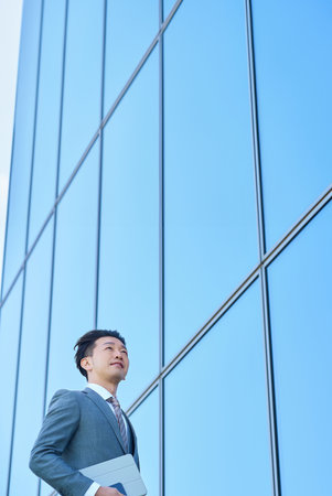Businessman in a suit looking up at the sky outdoorsの写真素材