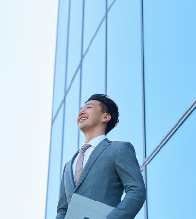 Businessman in a suit looking up at the sky outdoorsの写真素材