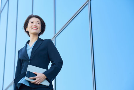 Business woman in a suit looking up at the sky outdoorsの写真素材