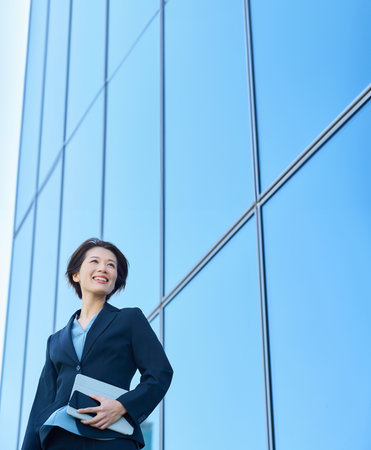 Business woman in a suit looking up at the sky outdoorsの写真素材