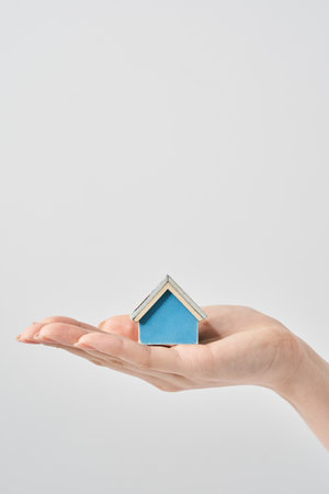 A house model held in the palm of a woman's hand and white backgroundの写真素材
