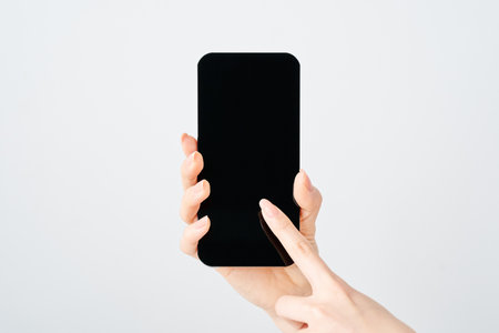 Hand of a woman holding a smartphone and white backgroundの写真素材