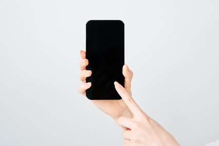 Hand of a woman holding a smartphone and white backgroundの写真素材