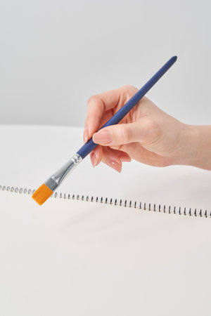 Woman's hand holding a paintbrush and white background