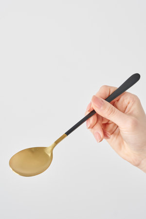 Woman's hand holding a spoon and white backgroundの写真素材