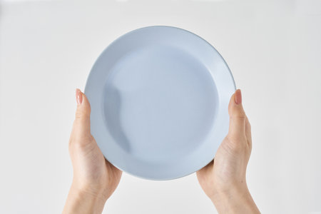 Woman's hand holding an empty plate and white backgroundの写真素材