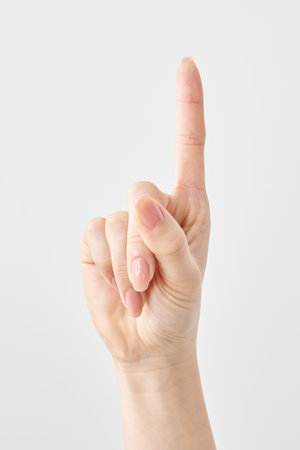A woman's index finger pointing upwards and white backgroundの写真素材