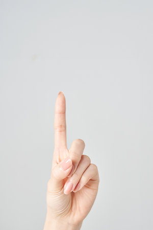 A woman's index finger pointing upwards and white backgroundの写真素材