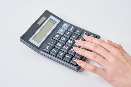 Hand of a woman using a calculator and white backgroundの写真素材