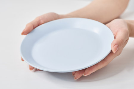Woman's hand holding an empty plate and white backgroundの写真素材