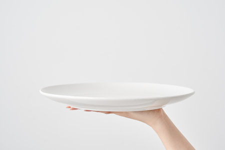 Woman's hand holding an empty plate and white backgroundの写真素材