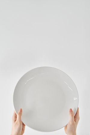 Woman's hand holding an empty plate and white background