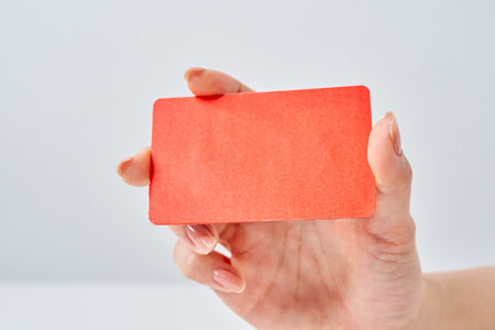 Woman's hand holding a red card and white backgroundの写真素材