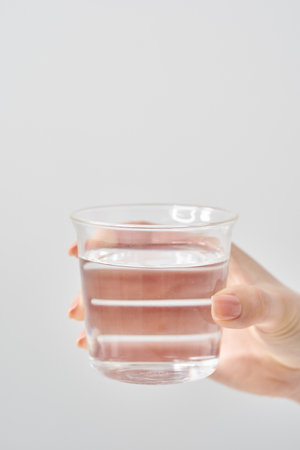 Woman's hand holding a glass of water and white backgroundの写真素材