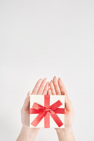 A woman's hand holds a box wrapped for a giftの写真素材