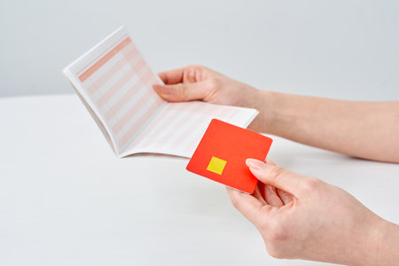 A woman's hand holding a bank passbook and card and white backgroundの写真素材
