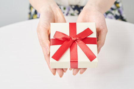 A woman's hand holds a box wrapped for a giftの写真素材