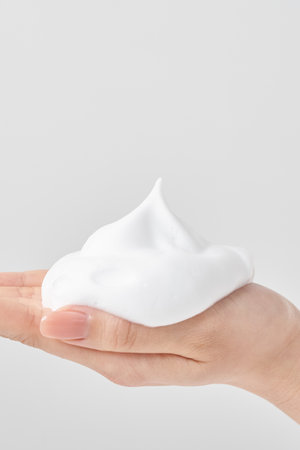 A woman's hand placing a lump of fine foam on her palm and white backgroundの写真素材