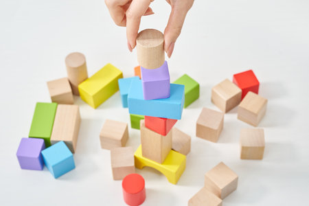 Hands of a woman stacking wooden blocks and white backgroundの写真素材