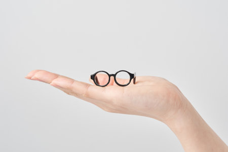 A model of glasses resting on a woman's palm and white backgroundの写真素材