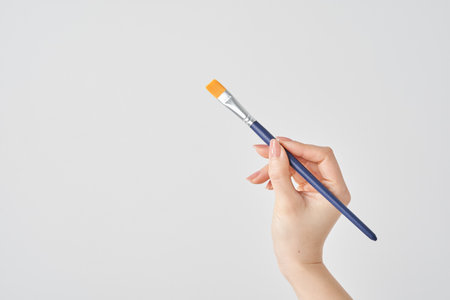 Woman's hand holding a paintbrush and white backgroundの写真素材
