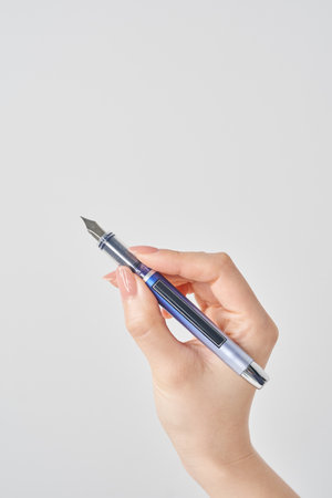 woman's hand holding a fountain pen and white backgroundの写真素材