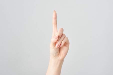 A woman's index finger pointing upwards and white backgroundの写真素材