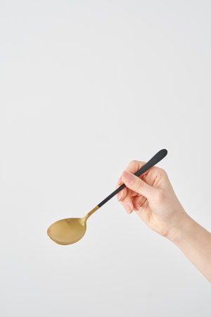 Woman's hand holding a spoon and white backgroundの写真素材