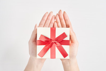 A woman's hand holds a box wrapped for a giftの写真素材