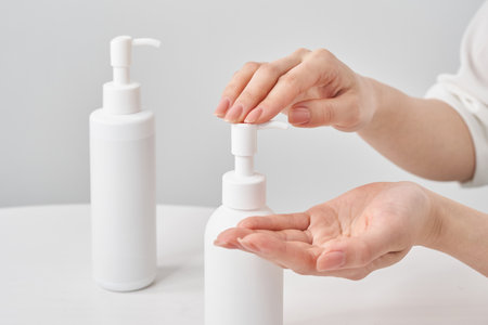 woman's hand and white bottle on the tableの写真素材