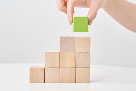 Hands of a woman stacking wooden blocks and white backgroundの写真素材