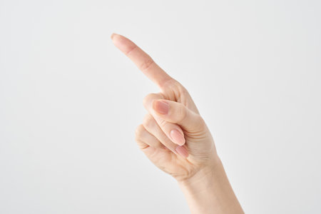 A woman's index finger pointing diagonally upwards and white backgroundの写真素材