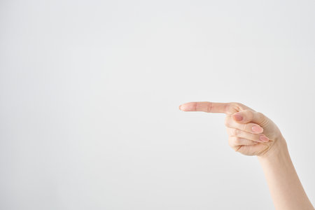 Woman's index finger pointing to the side and white backgroundの写真素材