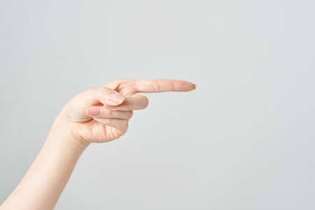 Woman's index finger pointing to the side and white backgroundの写真素材