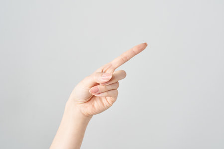 A woman's index finger pointing diagonally upwards and white backgroundの写真素材