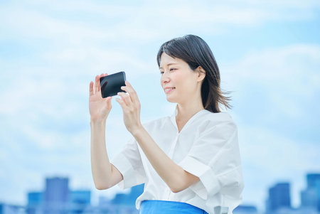 Young woman looking at smartphone screen outdoorsの写真素材