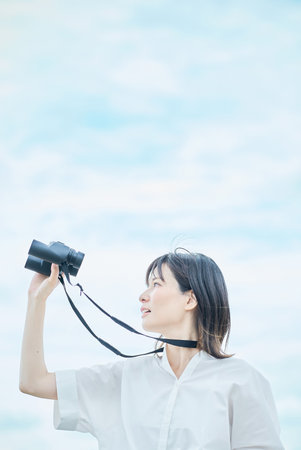Young woman looking at distant view through binocularsの写真素材
