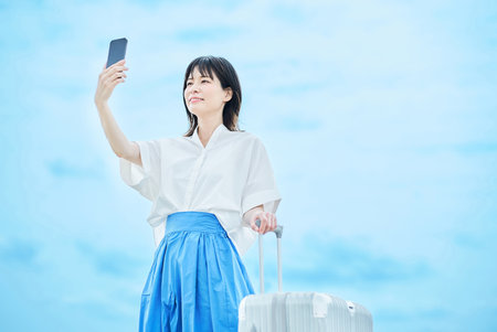 Young woman walking with suitcase outdoorsの写真素材