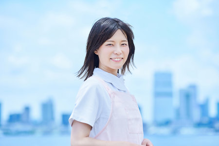 A young woman wearing a white coat and apron outdoorsの写真素材