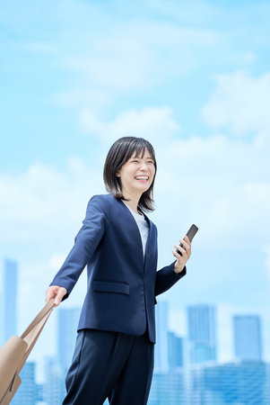 A young woman in a suit commuting to work on fine dayの写真素材