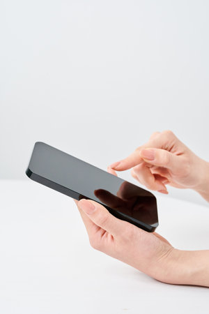 Hand of a woman holding a smartphone and white backgroundの写真素材