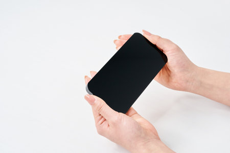 Hand of a woman holding a smartphone and white backgroundの写真素材