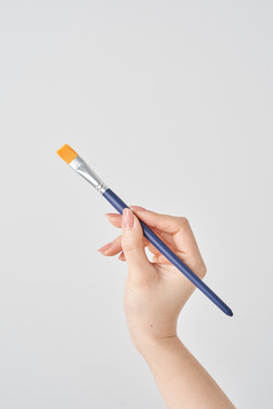 Woman's hand holding a paintbrush and white backgroundの写真素材