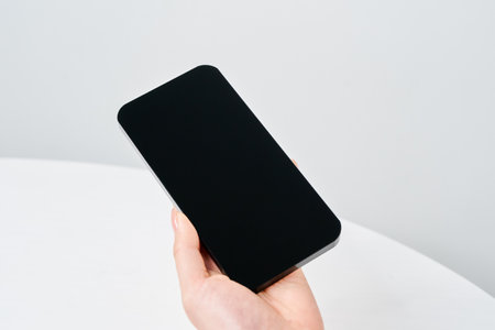 Hand of a woman holding a smartphone and white backgroundの写真素材