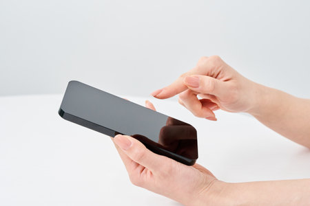 Hand of a woman holding a smartphone and white backgroundの写真素材